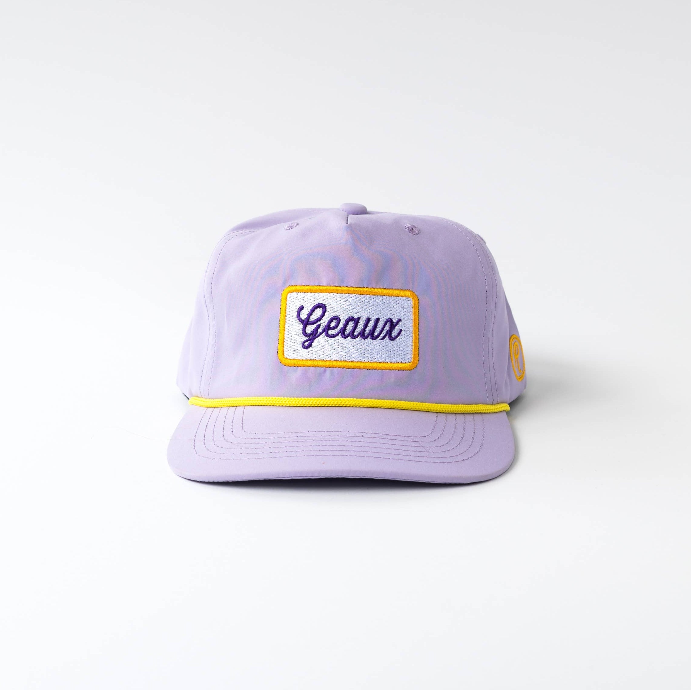 A light purple baseball cap with a yellow embroidered border around a front patch that reads 'Geanx' in purple script, and a thin yellow stripe along the brim, photographed against a light gray gradient background.