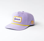 A light purple baseball cap with a yellow embroidered border around a white front patch reading 'Gaul' in blue script, and a small yellow circular patch on the side, photographed on a light gray background.